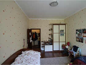 белые дверцы коричневого шкафа с открытыми боковыми полками у открытых дверей спальни в квартире педагога