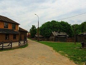 неширокая улица с трактиром в желтом двухэтажном доме с одной стороны и рядом жилых деревянных домиков с участками с другой