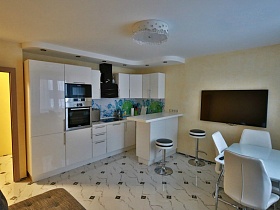белая мебель в светлой просторной кухне молодежной квартиры высотки в Новострое