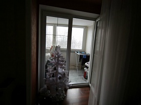 белоснежная новогодняя елочка у открытой двери на застекленную лоджию в семейной трешки