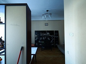 вид на модульную картину в черно-белом цвете у стены гостиной из зоны кухни квартиры художника в сталинке