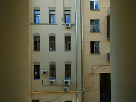 лепнина на окнах соседних квартир жилого многоэтажного дома из окна современной скандинавской квартиры