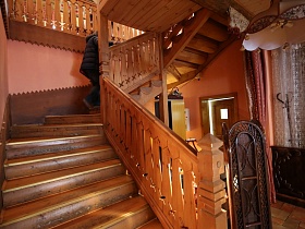 деревянные ступени лестницы с деревянными резными перилами, ведущие на мансарду ресторана, построенного из бревен в стиле сруба