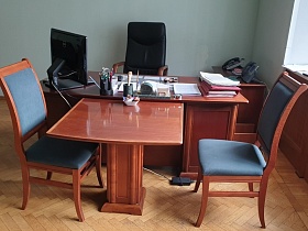 монитор и клавиатура, папки с бумагами, канцелярские принадлежности на поверхности коричневого деревянного письменного стола рабочего кабинета КГБ СССР