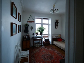 большой красный ковер и манекен на тумбочке в углу  спальной комнаты сталинки