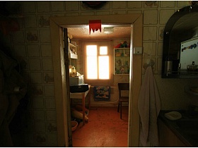 розовое полотенце на крючке у зеркала с полочкой над раковиной в кухне зеленого дачного домика на 2 семьи