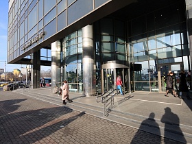 ступени крыльца с перилами, колонами у центрального входа в красивое здание современного бизнес-центра с офисами, паркингом и вертолетной площадкой