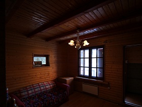 цветочные плафоны подвесной люстры на потолке просторной комнаты с деревянным потолком, стенами и полом оригинальной загородной дачи