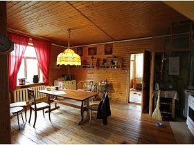 желтый абажур посередине комнаты над обеденным столом в зоне кухни деревянной дачи музыканта