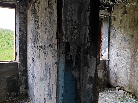 разрушенные стены со старой отслоившейся побелкой и краской  внутри кирпичного двухэтажного здания заброшенного лагеря на берегу водохранилища
