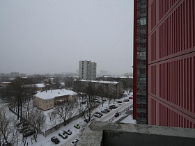 с балкона хорошо просматривается снежная дорога и парковка для машин