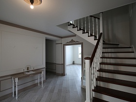 коричневые полированные ступени и перила красивой белой деревянной лестницы на второй этаж современного деревянного коттеджа