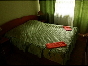 зеленое стеганное покрывало на деревянной кровати в комнате с светло зелеными обоями
