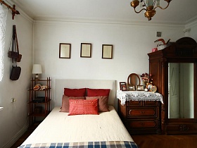 большая кровать между старинной этажеркой и комодом в спальне сталинки