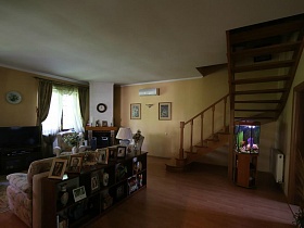 часы на камине, кондиционер и картины на стене у деревянной лестнице на второй этаж лесной дачи в соснах