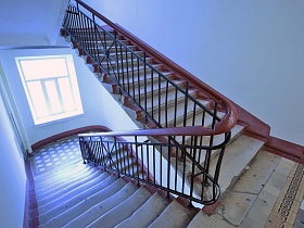 двухцветная плитка на полу лестничной площадки с большим окном у ступеней бетонной лестницы с перилами в подъезде жилого дома на Новослободской