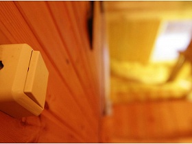 квадратный белый выключатель с кнопкой на деревянной стене дачи