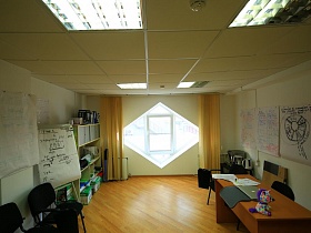 Просторная, хорошо освещенная комната от необычного окна в офисе рекламного агентства