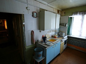 эмалированное ведро с водой на табурете у стены с часами в кухне дачи