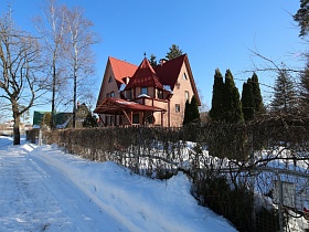 неординарный загородный дом с башней в сказочном стиле на заснеженном участке с высокими елями