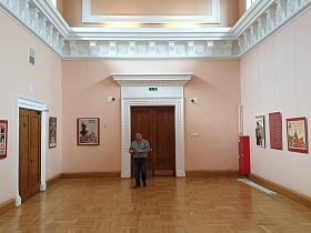 огромный светлый зал с нежно розовыми стенами, белой лепниной на стенах и над входной деревянной дверью в выставочной галерее СССР