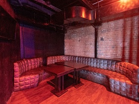 два коричневых раскладных стола у полукруглого большого дивана в уютной зоне отдыха кафе-бара лофт на втором этаже молодежного клуба