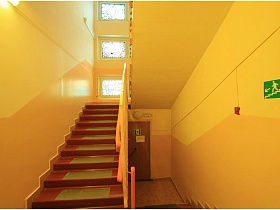 коричневые ступени лестницы с желтыми стенами в одном крыле детского сада