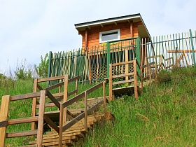 многочисленные ступени деревянной лестницы с площадками к жилому дому на крутом берегу реки