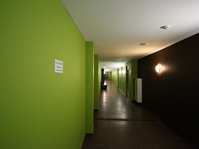 белый потолок, салатовые и коричневые стены длинного коридора фитнес клуба с указателем запасного выхода