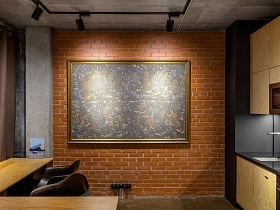 большая картина в деревянной раме на стене из красного кирпича в современной студии в стиле хай тек в серых тонах