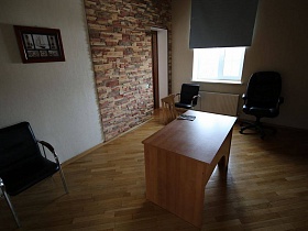 стол посередине рабочей комнаты с черными креслами у стены