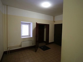 темнокоричневые двери квартир на площадке с квадратной плиткой на полу на этажах современного многоэтажного дома