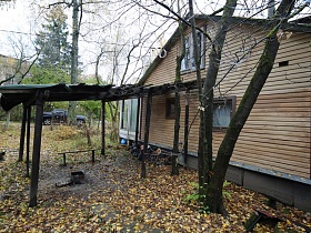 разрушенный деревянный навес без крыши у небольшого жилого домика отшельника среди новостроек