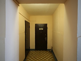 шахматная плитка на полу между квартирами на лестничной площадке со светлыми стенами в подъезде жилого дома