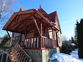 высокая лестница с резными металлическими перилами загородного дома в сказочном стиле с башней на высоком цоколе