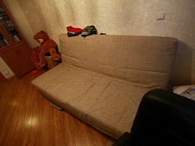 песочный диван у стены в гостиной обычной двухкомнатной квартиры в новострое
