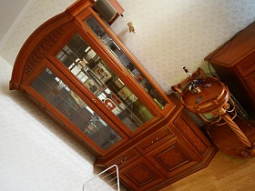  деревянный сервировочный столик у шкафа с множеством икон на полках под стеклом в углу гостиной трехкомнатной актерской квартиры