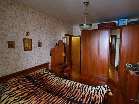 трюмо у деревянной кровати с леопардовым покрывалом в спальне обычной квартиры
