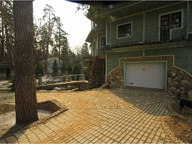 выложенные тротуарной плиткой и диким камнем дорожки к воротам гаража сказочного дома для съемок кино