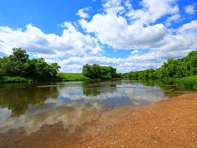 песчанный берег петляющего устья реки в живописном месте-холмогоры под ярко-синим небом с белыми облаками