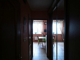  обеденный стол с зеленой клетчатой скатертью на кухне  в зеркальном отражении шкафа купе в длинном коридоре трешки