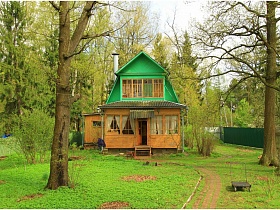 общий вид двухэтажной деревянной дачи с дорожкой на зеленом участке