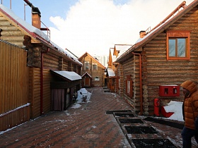 деревянные бревенчатые домики с треугольной крышей под снегом на улице банного комплекса