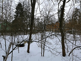 сугробы снега на просторном участке профессорской двухэтажной дачи с овальной террасой советского времени за забором