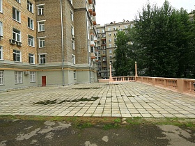 придомовая территория сталинского высотного дома с квадратной плиткой и невысоким бетоным забором