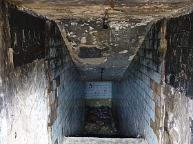 ужасное и грязное полуподвальное помещение с отслоившейся голубой квадратной плиткой на стенах заброшенного лагеря на берегу водохранилища