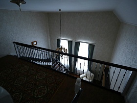 ковер на полу лестничной площадки светлой высокой гостиной с люстрой на потолке кирпичного добротного дома