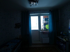 общий вид голубой детской спальной комнаты с кроватью в виде машины, изображением машин на дверцах шкафов и ковром на полу