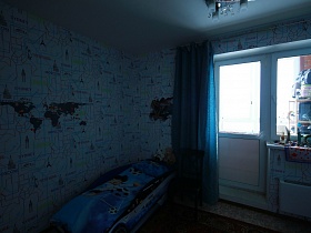 голубая спальня с детской кроватью в виде машинки и голубыми шторами на окне с балконной дверью простой современной трехкомнатной квартиры