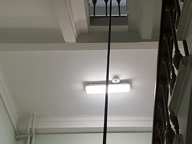 лампа дневного освещения на высоких белых потолках лестничной клетки подъезда сталинской высотки советского времени